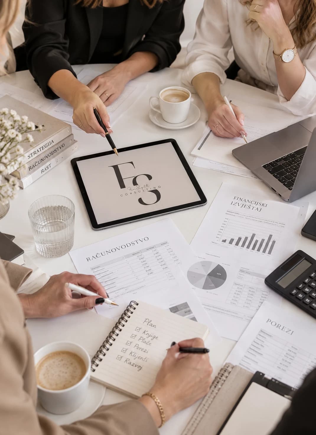 Tim Fin Sight Consultinga za stolom s financijskim izvještajima, tabletom i bilježnicom s planom